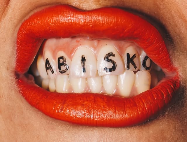 Labios rojos con ABISKO escrito en los dientes